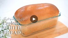 a loaf of white bread sitting on top of a cutting board next to a plant