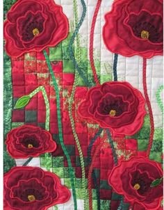 red flowers are on the side of a quilted wall hanging ornament with green stems and leaves