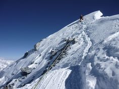 a man climbing up the side of a snow covered mountain