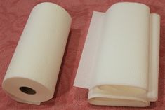 two rolls of toilet paper sitting on top of a pink towel next to each other