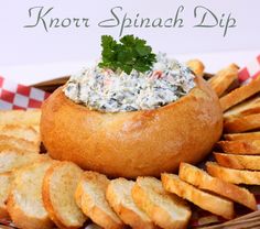 a bread bowl filled with blue cheese dip surrounded by crackers on a checkered table cloth