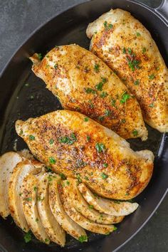 three pieces of chicken in a skillet with parsley and seasoning on top