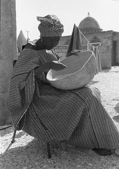 a woman is sitting on the ground with a hat in her hand and looking at something