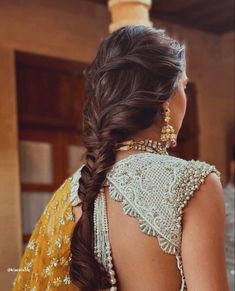 a woman with long hair wearing a yellow sari and gold jewelry, looking off to the side