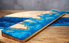 two wooden paddles sitting on top of a blue and white surfboard with waves painted on them