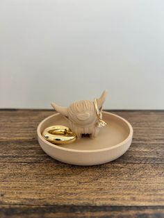 a small white bird sitting on top of a wooden table next to a gold ring