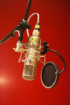 a microphone is hanging from the ceiling with a red wall in the backround