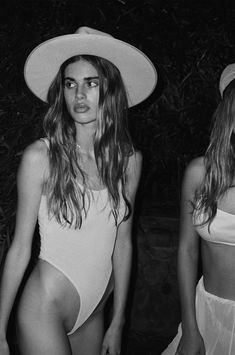 two women in swimsuits and hats standing next to each other