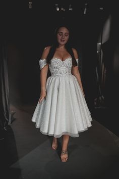 a woman wearing a white dress standing in the dark