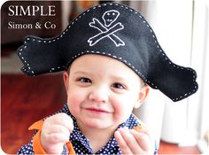 a little boy wearing a pirate hat and pointing at the camera