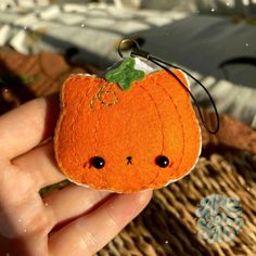 a hand holding an orange cat ornament on top of a woven table cloth