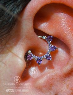 a close up of a person's ear with purple and white stones