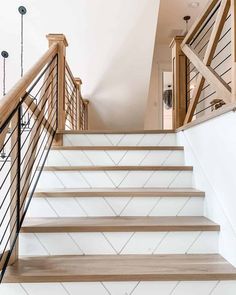 a staircase with wooden handrails and white tile on the bottom, leading up to an upper floor