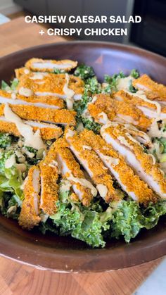 a salad with chicken and ranch dressing in a brown bowl on a wooden counter top