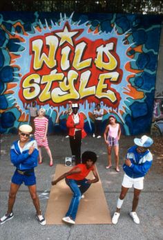 a group of people standing in front of a graffiti wall