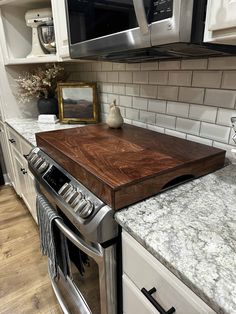 a kitchen counter with a cutting board on it in front of a microwave and stove