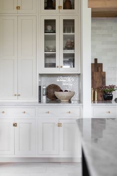 a kitchen with white cabinets and marble counter tops in front of an open cabinet door