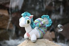 a crocheted stuffed animal sitting on top of a rock next to a waterfall