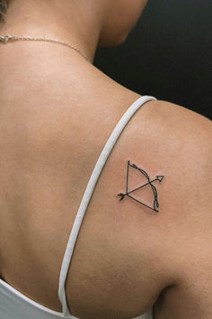 the back of a woman's shoulder with a bow and arrow tattoo on it