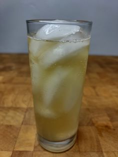 a glass filled with ice sitting on top of a wooden table