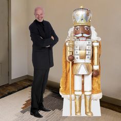 a man standing next to a large wooden nutcracker