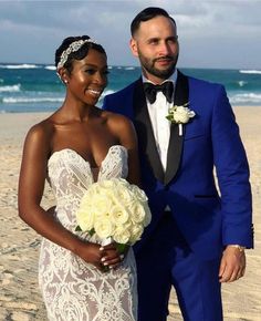 a bride and groom standing on the beach