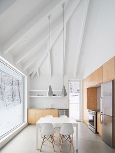 an open kitchen with white walls and wooden cabinets, along with a dining table that has four chairs in front of it