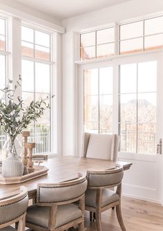 a dining room table with chairs and a vase filled with flowers on top of it