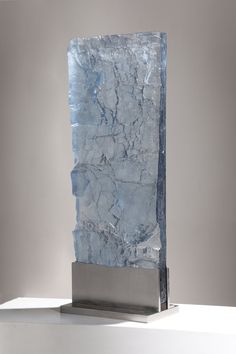 a blue stone sculpture sitting on top of a white table next to a gray wall