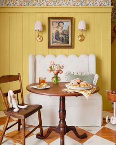 a small table and chairs in a room with yellow walls, checkered flooring