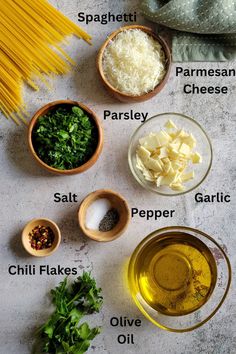 ingredients to make pasta laid out in bowls on a white counter top, including parmesan cheese, parsley, pepper, garlic and olive oil