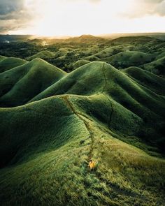 an aerial view of green hills and trees