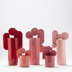 pink and red vases sitting on top of each other in front of a white background