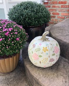 two pumpkins sitting on the steps next to some flowers