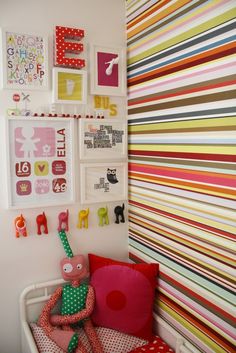 a child's room with colorful wallpaper and pictures on the wall, including a stuffed animal