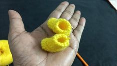 a hand holding two small yellow crocheted objects