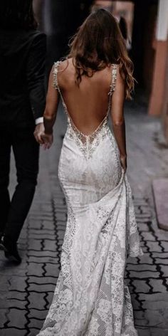 the back of a woman's dress as she walks down a cobblestone street