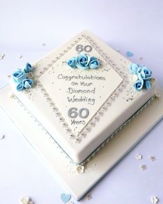 a square cake decorated with blue flowers and the words 80th anniversary written on it