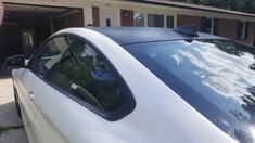 a white car parked in front of a building next to a parking meter and trees