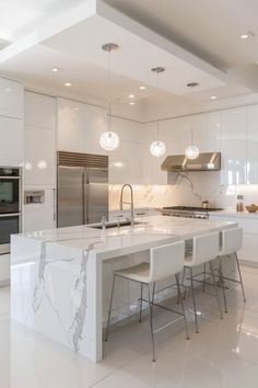 a large white kitchen with marble counter tops and island in front of the stove top oven