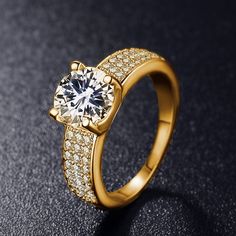 a gold ring with diamonds on the sides and a center stone surrounded by small pave stones