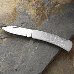 a knife sitting on top of a rock next to a stone wall with writing on it