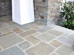 a white door is in front of a stone wall and planter on the patio