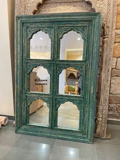 an ornate green cabinet with mirrors on the front and back sides, in a living room