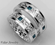 two wedding bands with blue stones in the center and an intricate design on each band