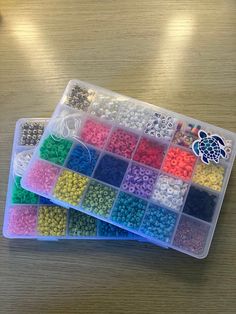 two plastic containers filled with lots of different colored beads on top of a wooden table