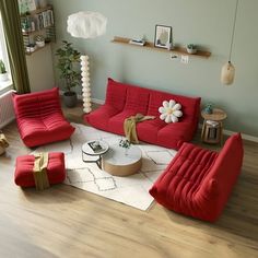 a living room filled with red couches and chairs next to a white rug on top of a hard wood floor