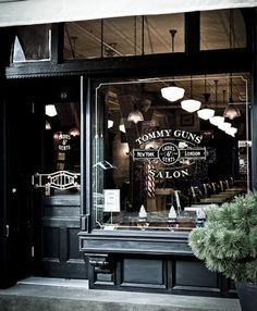 a store front with many lights hanging from it's windows and plants in the window