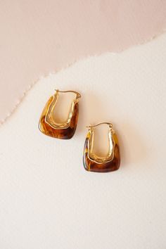 Introducing the Benny Amber Horseshoe Earrings, a stylish blend of whimsy and sophistication. These earrings feature a horseshoe-shaped design crafted from amber-colored lucite, accented with elegant gold details. Perfect for adding a touch of playful elegance to your ensemble, they effortlessly transition from day to night with their versatile charm. The Benny Amber Horseshoe Earrings are ideal for those who appreciate accessories that combine unique design with timeless appeal, making them a standout addition to any jewelry collection. Horseshoe Earrings, Amber Earrings, Amber Color, Earring Sale, Gold Details, Gold Accents, Shoe Sale, Summer Essentials, Earring Necklace