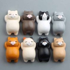 small plastic cat figurines sitting in a row on a gray surface, with their eyes closed